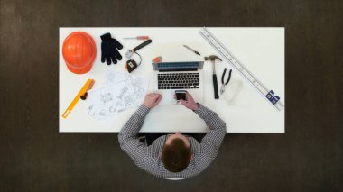 Cep telefonuyla masasında oturan ofis mühendisi