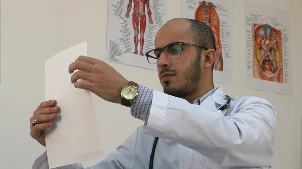 Jonge mannelijke arts zorgvuldig bestuderen cardiogram — Stockfoto