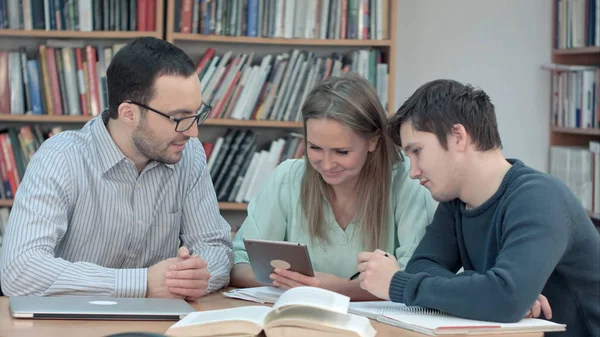 Nauczyciel z grupą studentów pracujących na cyfrowy tablet w bibliotece — Zdjęcie stockowe