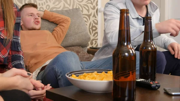 Grupo de amigos sentados no sofá, assistindo TV juntos e bebendo cerveja — Fotografia de Stock