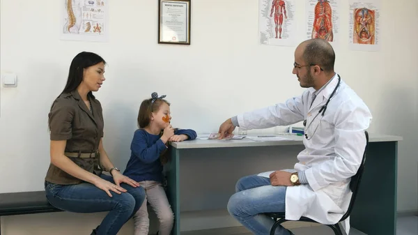 Feliz joven madre pagando médico para su hija examen médico — Foto de Stock