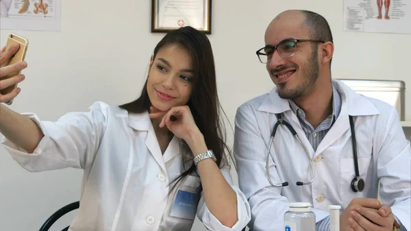 Молодий лікар і гарненька медсестра приймає селфі по телефону на робочому столі — стокове фото