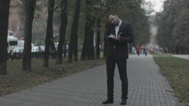 Telefonla konuşurken ve günlüğünde, yazma park sokakta sakallı işadamı yeşil park adlı Notes ile çalışma.