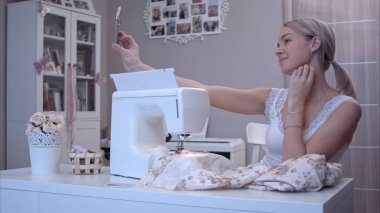 Genç kadın dikiş makinesi yanında otururken ona telefon ile selfies alarak