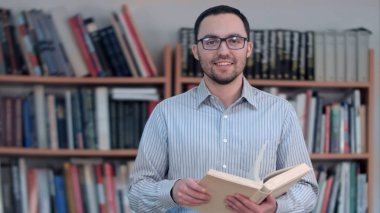 Kitap ve kameraya bakarak Genç öğretmen