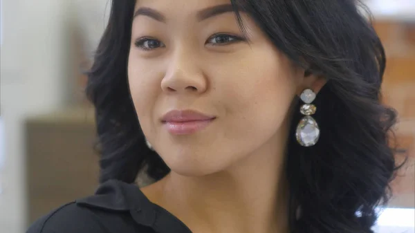 Beautiful asian woman trying on earrings in front of the mirror and smile to reflection