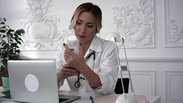 Serieuze vrouwelijke arts werkt aan haar laptop en Smart Phone. — Stockfoto