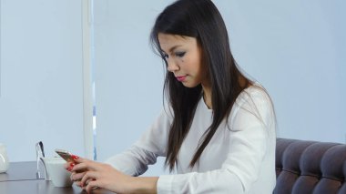 Güzel genç kadın telefonunu bir kafede kontrol