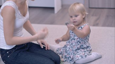 Mutlu genç anne ve küçük kızı halı üzerinde oturan mücevher kutusu keşfetmek