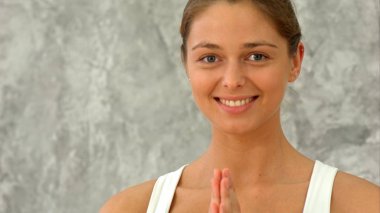 Kameraya bakarak namaste hareketi el ile yoga yaparken mutlu olgun kadın
