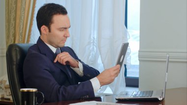 Zarif işadamı onun elbise ve modern tablet vasıl seyir saç düzeltme