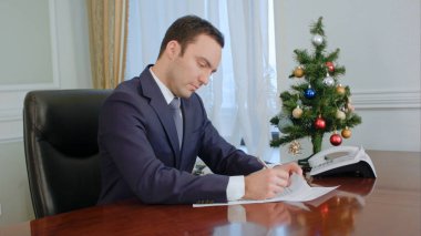 Belgeleri okuma ve yeni yıl ağacı yakınındaki Masası tarafından imzalanması genç işadamı
