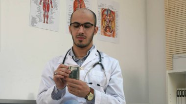 Para sayma ve cebine koyarak memnun erkek doktor