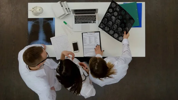 Equipo de médicos mirando el ordenador portátil y analizando rayos X en el consultorio médico — Foto de Stock