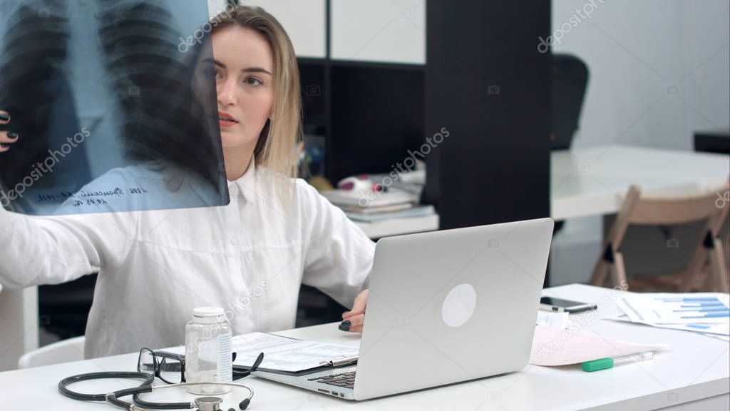 Female doctor examining xray image sitting in the office