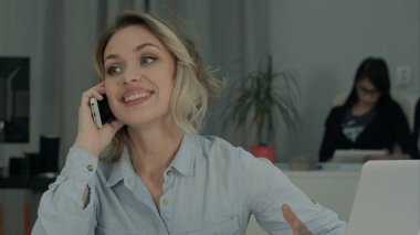 Ofis Masası oturma ve cep telefonuyla konuşurken gülümseyen genç kadın