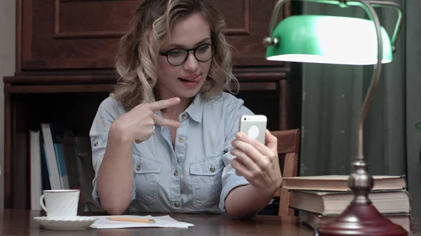 Молодая женщина в очках делает селфи по телефону на работе — стоковое фото