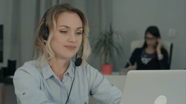 Genç bir kadın işçi ofiste dizüstü üzerinden görüntülü arama yapma