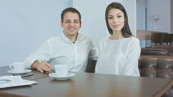 Casal de negócios alegre conversando com a câmera sentada em um café — Fotografia de Stock