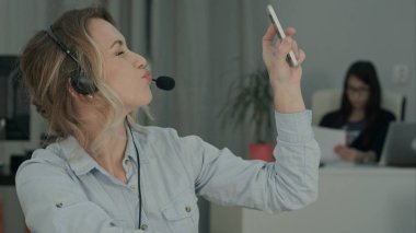 Genç ve güzel ofis işçi işyerinde komik selfies alarak kulaklık