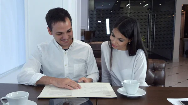 Pareja mirando el menú y eligiendo qué pedir para el almuerzo — Foto de Stock