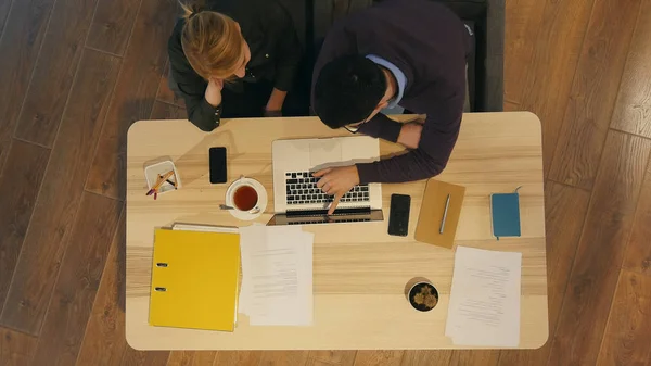 Gestionnaire et son joli jeune collègue assis au bureau et travaillant sur la présentation de l'entreprise — Photo