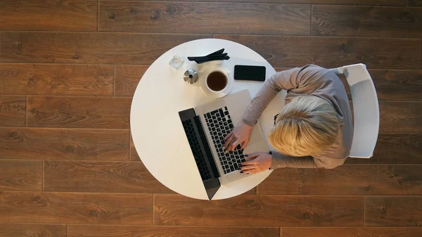 Молода жінка використовує ноутбук, сидячи в кафе — стокове фото