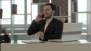 ofiste cep telefonunda konuşan mutlu gülümseyen genç adam