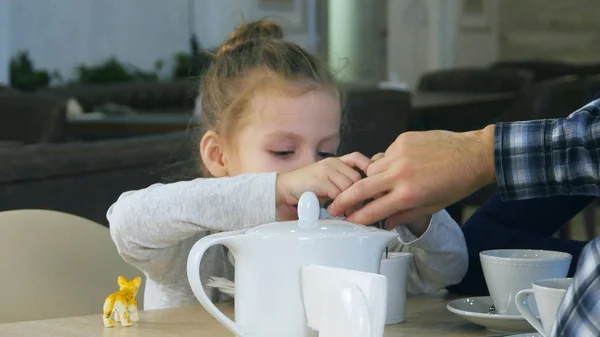 Sarışın sevimli kız onun fincan çay şekeri dener. Annesi ona yardımcı olur. — Stok fotoğraf