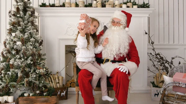 Litlle menina sacudindo seu presente de Papai Noel tentando adivinhar o que está dentro — Fotografia de Stock