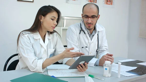 Bastante joven enfermera mostrando algo en la tableta a su colega masculino — Foto de Stock