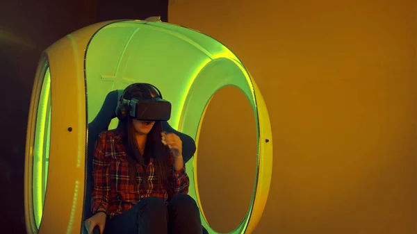 Młoda kobieta przeżywa wirtualnej rzeczywistości siedzi w interaktywne ruchome krzesło — Zdjęcie stockowe