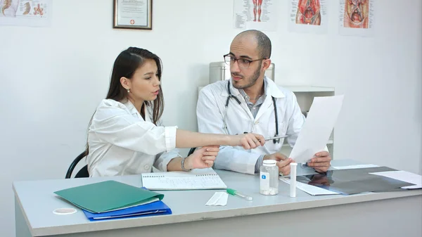 Médecin montrant à sa stagiaire comment lire un cardiogramme pendant qu'elle prend des notes — Photo