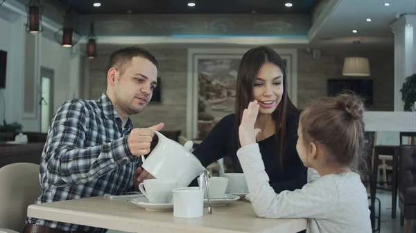 Отец наливает чай жене и дочери в ресторан. Мать ласкает дочь по голове . — стоковое фото