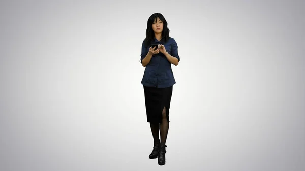 Jóvenes mujeres asiáticas de pie con teléfono inteligente y hablando con una cámara sobre fondo blanco —  Fotos de Stock
