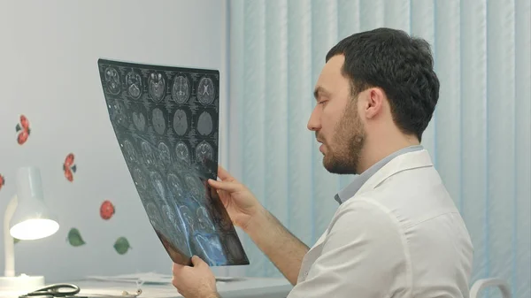Médico masculino concentrado mirando la radiografía en el consultorio médico — Foto de Stock