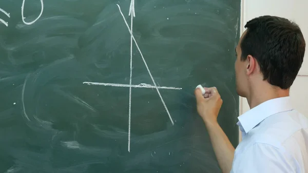 Joven profesor o estudiante dibuja un gráfico de líneas en una pizarra con fórmula — Foto de Stock