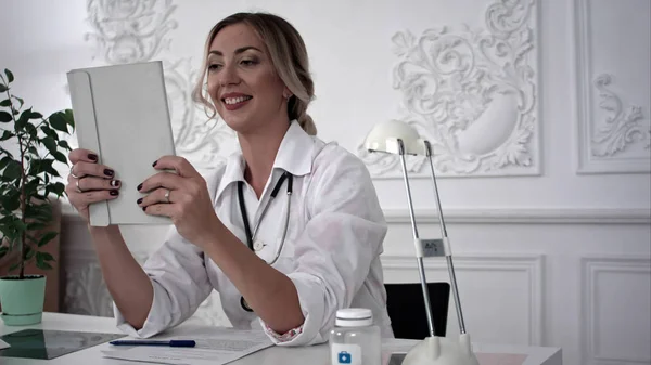 Жінка-лікар робить селфі на планшеті в офісі . — стокове фото