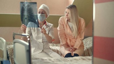 X-ışını tutarak ve genç kadın hasta yatağında oturup konuşmak profesyonel doktor