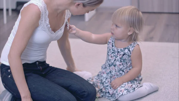 Mother and her little child trying brooches on each other