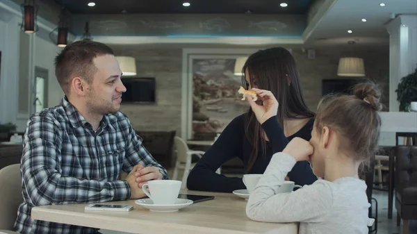 Воссоединение счастливой семьи в кафе. отец, мать и дочь улыбаются и болтают вместе . — стоковое фото