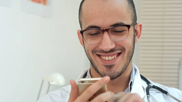 Medical worker checking his phone and laughing — Stock Photo, Image