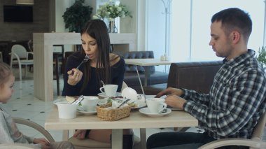 Babası ile karısı ve kızı kafede otururken diz üstü kullanarak. Anlama ve onu rahatsız edici değil kadın.