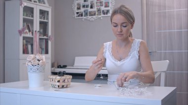 Genç kadın boncuklarını takı yapmak için malzeme çekme