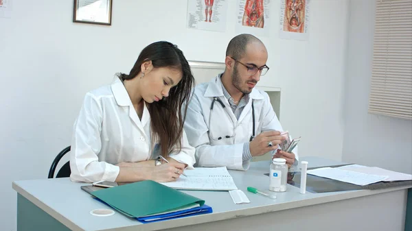 Homme médecin compter l'argent et le donner à son partenaire féminin — Photo