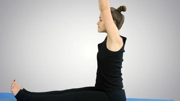 Giovane donna che allunga la gamba sul tappeto, praticando yoga su sfondo bianco — Foto Stock