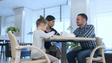 Anne, baba ve kızı kafede çay içme. Ebeveynler bir tartışmanın ardından telefon görüşmesi var.