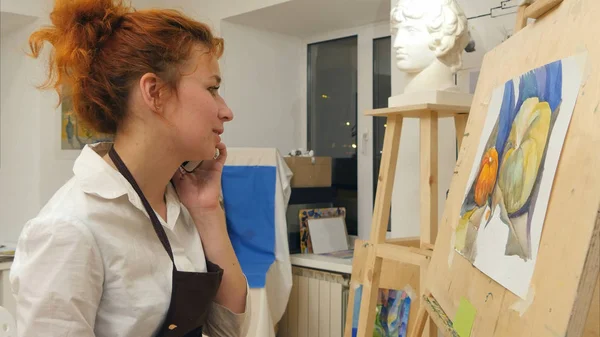 Mujer artista pintando una imagen mientras habla por teléfono — Foto de Stock