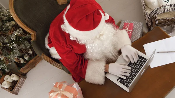 Noel Baba hediyeleri bir listesini yapmak üstünde onun laptop meşgul — Stok fotoğraf