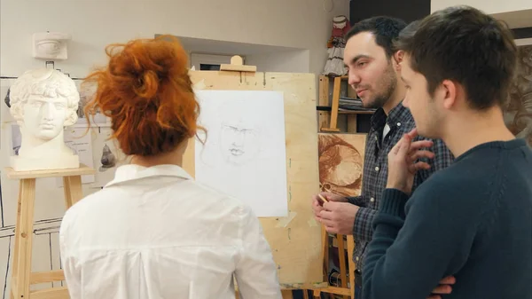 Professor de arte explicando dois alunos do sexo masculino como desenhar gesso elenco — Fotografia de Stock